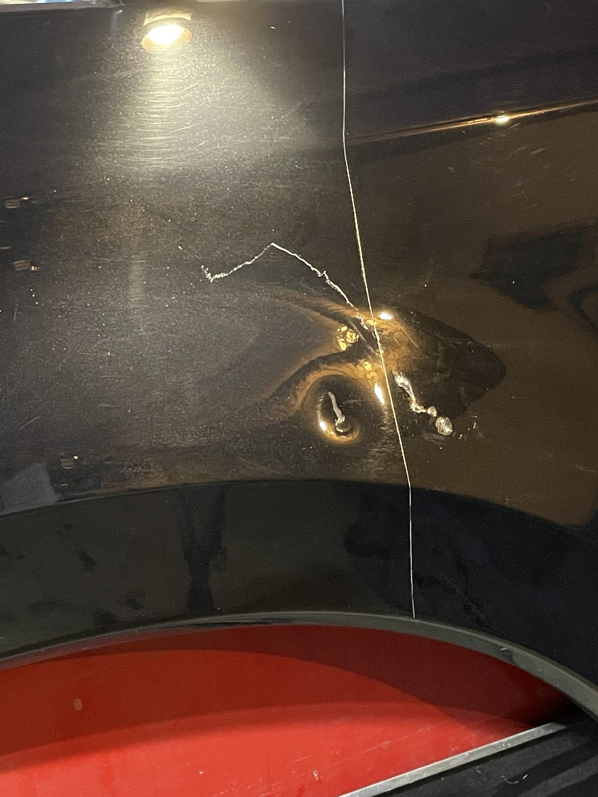 Paint chip and scratch damage on a black panel before repair in Prince George